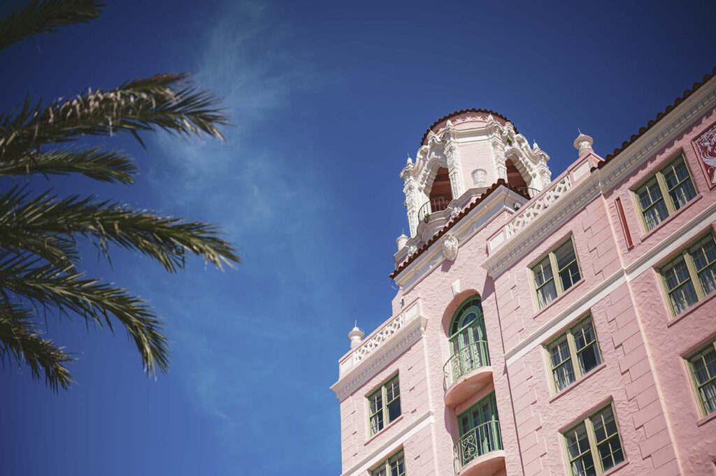 A pink building with a clock tower and palm trees. VINOY resort