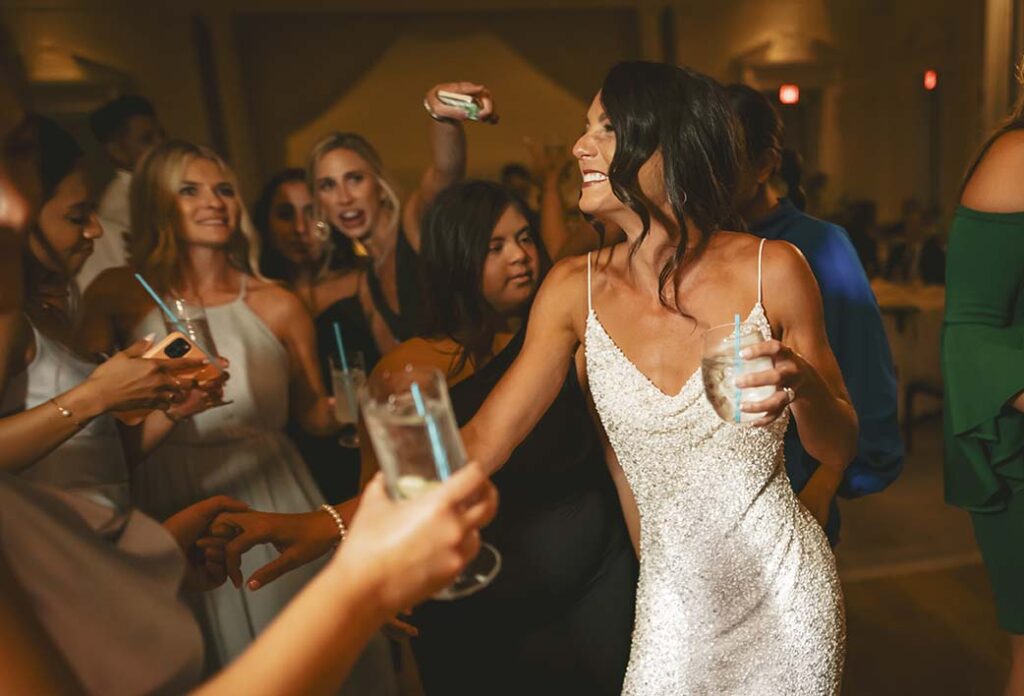 A bride is dancing with her friends at a wedding.