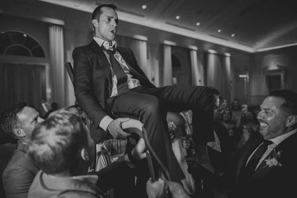 A man in a suit sitting on a chair at a wedding.