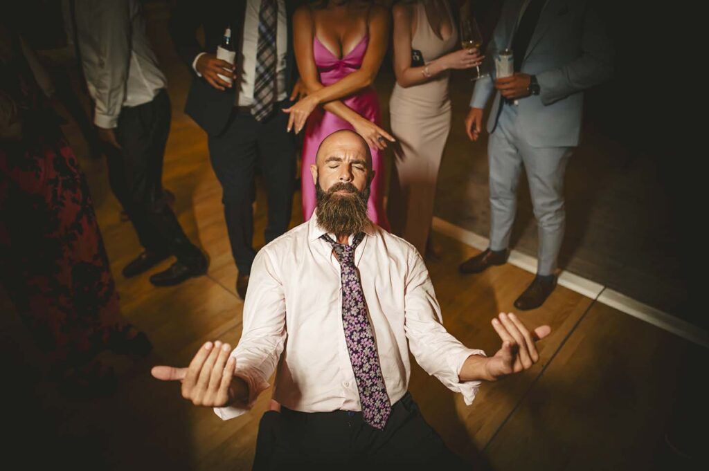A man with a beard meditating in front of a group of people.