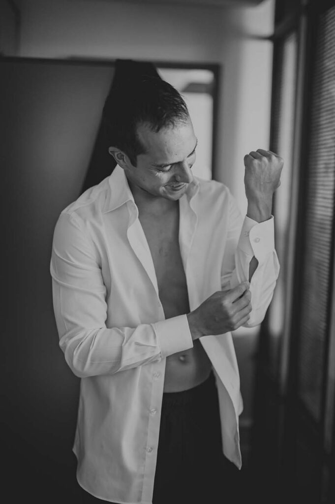 Black and white photo of a man putting on his shirt.